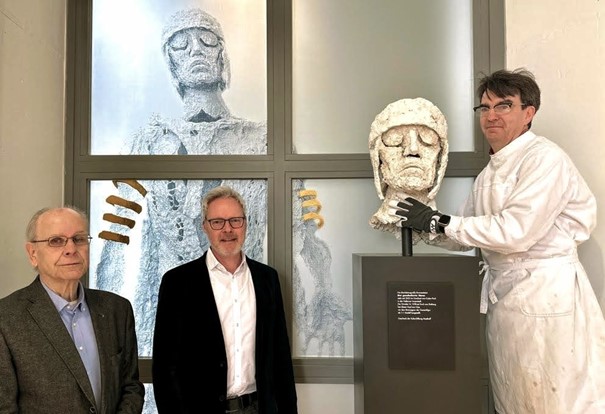 Dr. Horstfried Masthoff von der KulturStiftung Masthoff und Dr. Josef Mühlenbrock, Leiter des LWL-Römermuseums, wohnen der Aufstellung des neuen Exponats durch den Restaurator der LWL-Archäologie für Westfalen, Andreas Weisgerber (v.l.), bei.